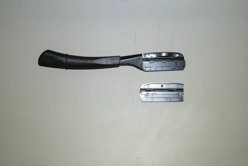A swappable blade, fixed handle straight razor with the blade compartment open & parts shown